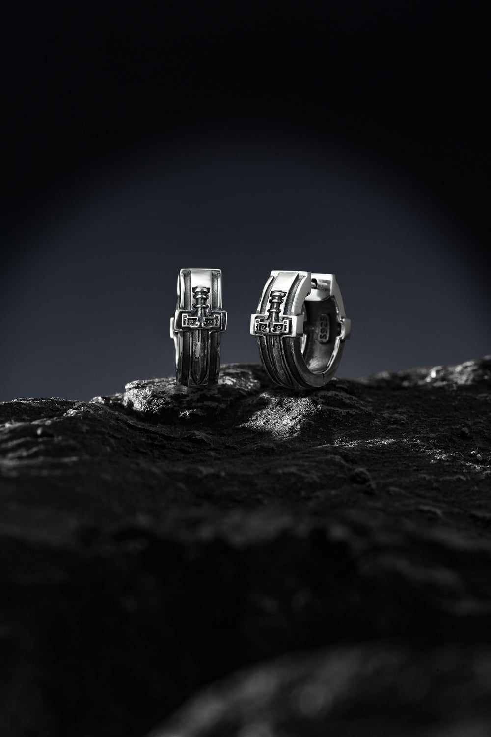 Boucles en argent posées sur une pierre texturée