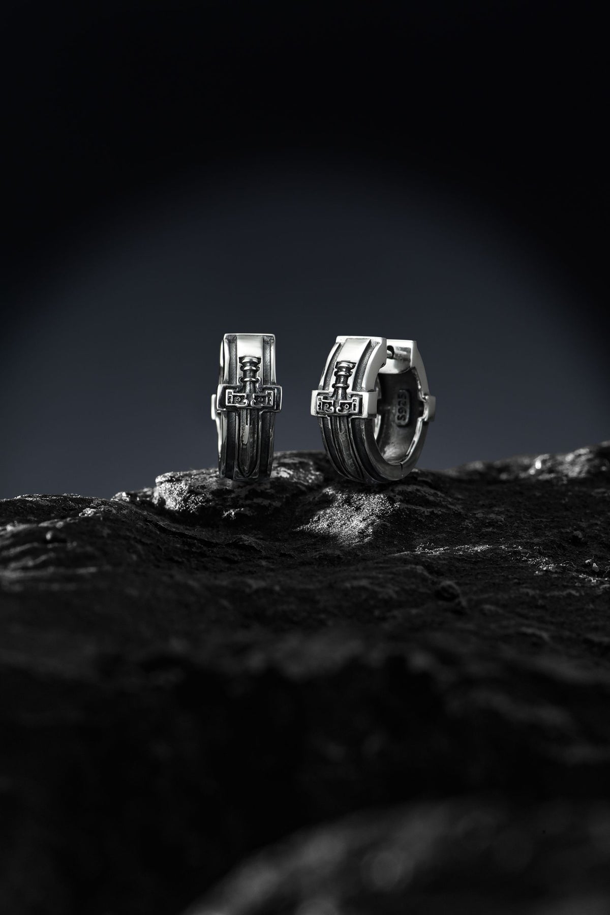 Boucles en argent posées sur une pierre texturée